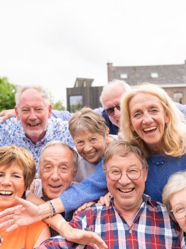 Carefree and happy elderly friends embrace joyfully and taking selfie outdoor in the garden.